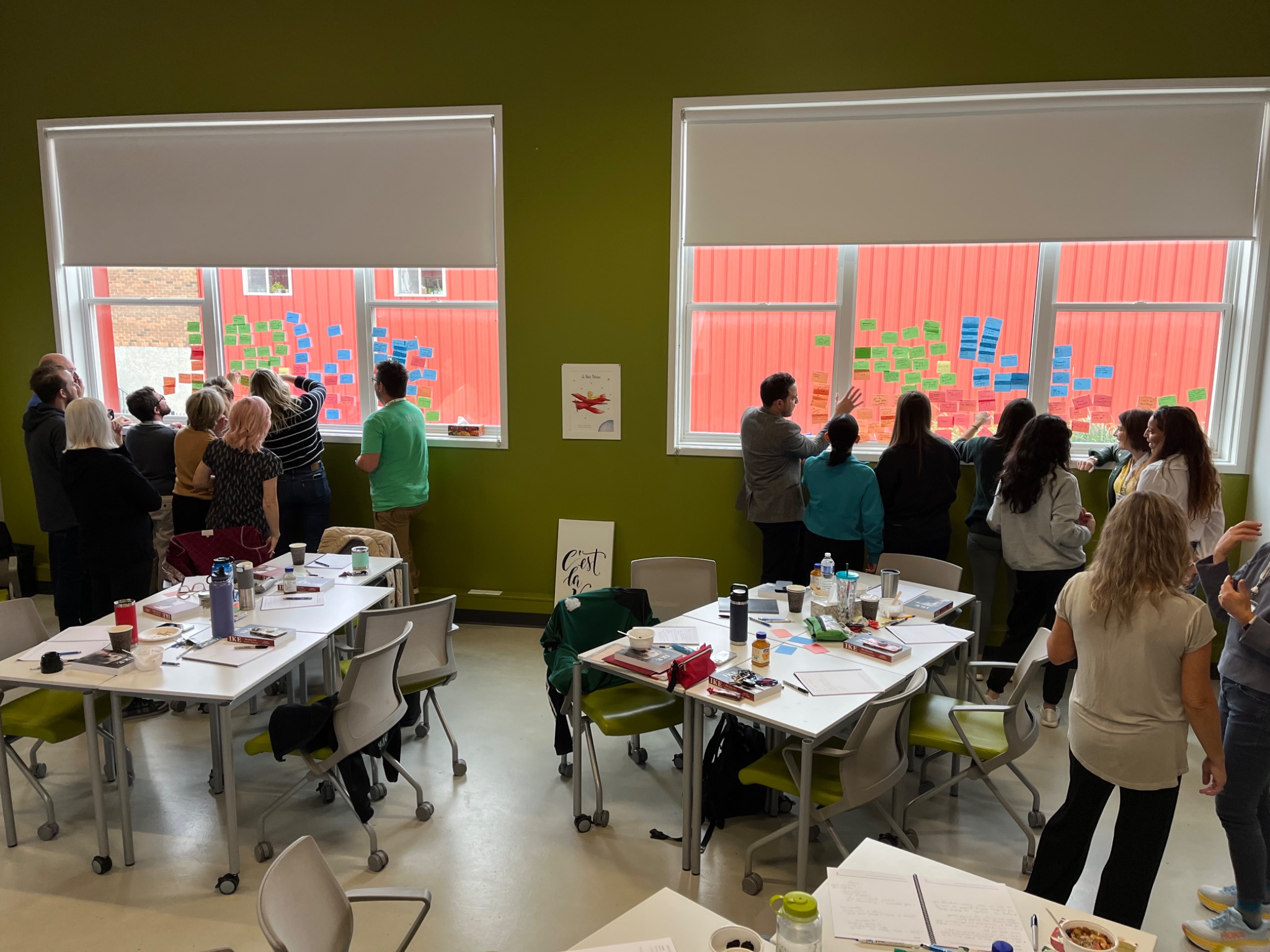 Workshop participants collaborating in groups with colourful notes covering the windows